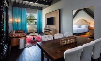 a modern living room with wooden flooring , blue curtains , and a dining table set for a meal at Hotel Nyack, A Joie de Vivre Hotel by Hyatt