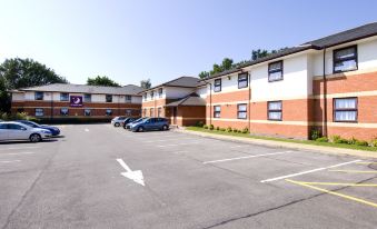 a parking lot with multiple cars parked in front of an apartment building under a clear blue sky at Premier Inn Fareham