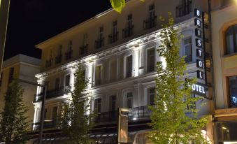 a large building with white and yellow lights on the balconies at night , illuminated by street lights at Bristol Hotel