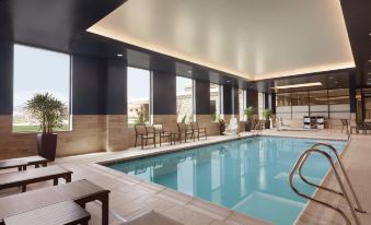 an indoor swimming pool surrounded by lounge chairs , with several people relaxing and enjoying their time at Embassy Suites by Hilton South Jordan Salt Lake City