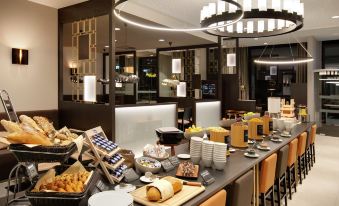 a dining area with a long buffet table filled with various food items and utensils at Hilton Garden Inn Zurich Limmattal