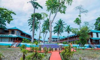 a tropical resort with lush greenery , wooden buildings , and a red path leading to the entrance at Holiday Inn Beach Resort