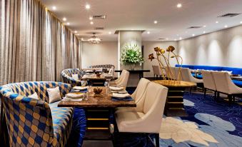a modern and elegant dining room with blue and white furniture , a large table , and flowers at The Park Chennai