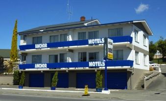 "a large white building with blue trim and a sign that reads "" anchor motel .""." at Anchor Motel