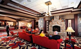 a spacious living room with two people sitting on red couches and a fireplace , enjoying their time together at Cherokee Casino West Siloam Springs Resort