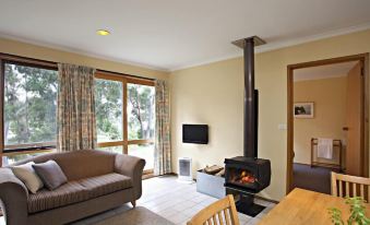 a cozy living room with a fireplace , a couch , a chair , and a dining table at Bruny Island Escapes and Hotel Bruny