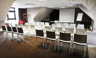 a conference room with rows of chairs arranged in a semicircle , ready for a meeting at Logis Golfe Hotel