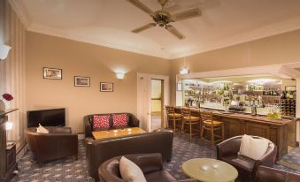 a cozy living room with a bar area , where several people are seated and enjoying themselves at Best Western New Holmwood Hotel