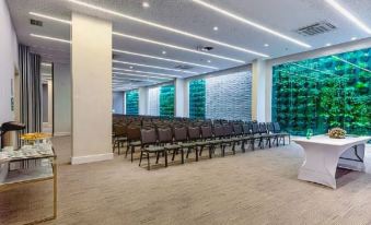 a large conference room with rows of chairs arranged in a semicircle , and a podium at the front of the room at CDesign Hotel