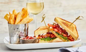 a white plate with a sandwich and french fries next to a glass of white wine at Courtyard Thousand Oaks Agoura Hills