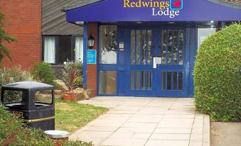 a red wings lodge building with a blue door and a golf cart in front at Redwings Lodge Rutland