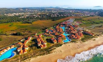 an aerial view of a resort on the beach , featuring multiple buildings and pools surrounded by grass and water at Búzios Beach Resort Luxo II