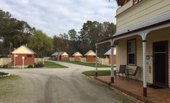 "a brick building with a sign that says "" pioneer "" is located on a street with palm trees" at Deniliquin Pioneer Tourist Park