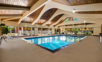 a large , well - maintained swimming pool is surrounded by a curved ceiling with exposed beams and windows at Best Western Prairie Inn  Conference Center