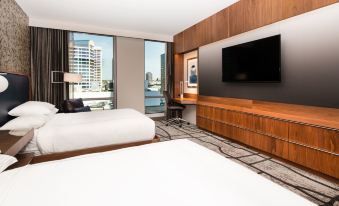 a hotel room with two beds , a large window offering a view of the city , and a flat - screen tv mounted on the wall at The Charter Hotel Seattle, Curio Collection by Hilton