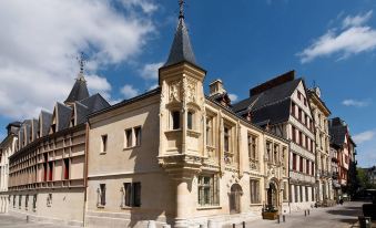 a traditional european building with a spire and flags on top , set against a blue sky at Hotel de Bourgtheroulde, Autograph Collection