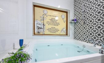 The bathroom features a large tub and a window that overlooks the outside, accompanied by an artwork at Gapyeong Dasom Pension