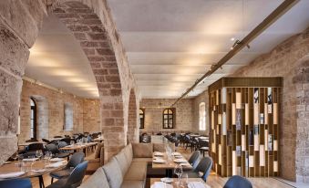 a modern restaurant with stone walls , wooden beams , and a dining area filled with tables and chairs at The Setai Tel Aviv, a Member of the Leading Hotels of the World