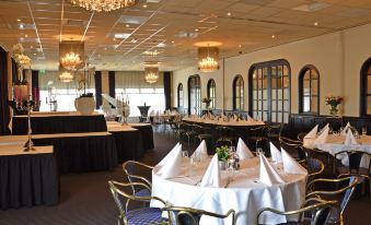 a large dining room with multiple tables and chairs set up for a formal event , possibly a wedding reception at Fletcher Hotel - Restaurant Heiloo