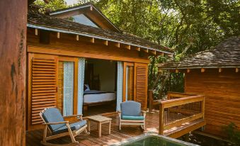 a wooden house with a deck , surrounded by trees and a pool , and equipped with comfortable seating at Aqua Nicaragua