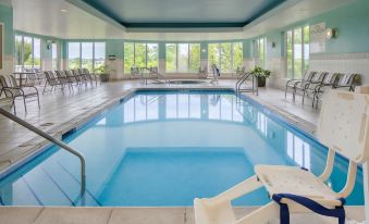 an indoor swimming pool with a clear blue water , surrounded by white chairs and tables , under a sunny sky at Hilton Garden Inn Omaha West