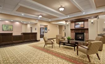a large , well - lit hotel lobby with a fireplace , seating area , and a reception desk , all decorated in warm colors at Homewood Suites by Hilton Rochester - Victor