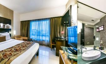 a modern hotel room with a bed , desk , and tv , as well as a bathroom area with a sink and mirror at The Regenza by Tunga