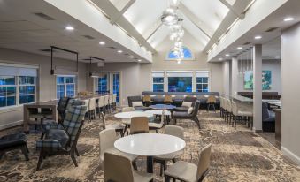 a large dining area with multiple tables and chairs , some of which are covered in white tablecloths at Residence Inn Boston Westford
