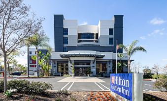 the hilton garden inn hotel is a modern , white building with blue signage and palm trees in front at Hilton Garden Inn Irvine Spectrum Lake Forest