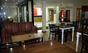 a modern , well - lit dining area with wooden tables and chairs , including a red and black striped couch at 247Hotel.Com
