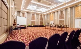 a large conference room with a red carpet , white walls , and multiple chairs arranged around a long table at Savero Hotel Depok