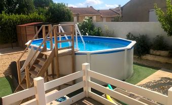 a backyard with a blue swimming pool , wooden decking , and stairs leading down to the pool at Les Amandiers