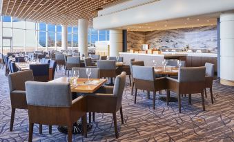 a large , modern restaurant with multiple dining tables and chairs arranged for guests to enjoy their meal at Pan Pacific Vancouver