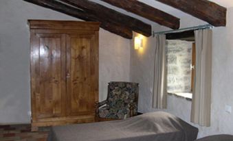 a bedroom with a wooden armoire , chair , and bed under a wooden ceiling with exposed beams at La Bergerie