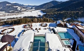 a snow - covered mountainous landscape with a swimming pool and buildings , taken from an aerial view at Alpin Panorama Hotel Hubertus