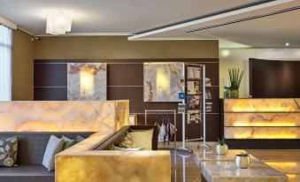 a modern living room with a large couch , tables , and paintings on the wall , creating an elegant and stylish atmosphere at Winter Garden Hotel Bergamo Airport