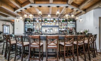 a bar area with a wooden counter , several chairs , and bottles on the counter , creating an inviting atmosphere at Briar Barn Inn