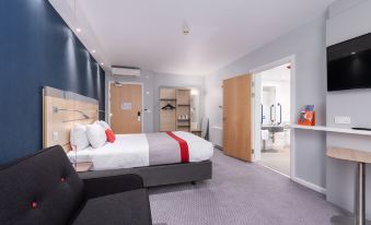 a modern hotel room with a bed , couch , and desk , as well as a view of the bathroom through an open door at Holiday Inn Express Burnley M65, Jct.10