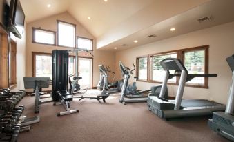 a well - equipped gym with various exercise equipment , including treadmills and weight machines , under a large window at The Deers Head Inn Tavern