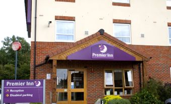 an exterior view of a premier inn hotel , with a sign above the entrance and multiple cars parked in front at Premier Inn Grantham