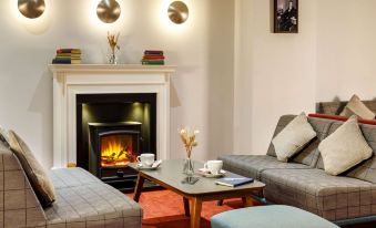 a cozy living room with two couches and a fireplace , creating a warm and inviting atmosphere at Mercure Telford Centre Hotel