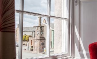 a view from a window , with a clock tower and buildings visible outside the window at The Inn at Brough