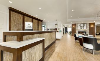 a modern hotel lobby with wooden flooring , a reception desk , and a staircase leading to the second floor at Homewood Suites by Hilton Augusta, ME