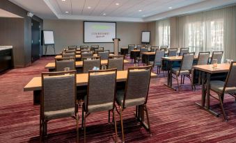 a conference room with rows of chairs arranged in a semicircle and a projector screen mounted on the wall at Courtyard Schenectady at Mohawk Harbor