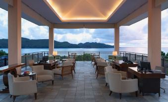 a modern , well - lit restaurant with outdoor seating and a view of the ocean , under a covered terrace at Raffles Seychelles