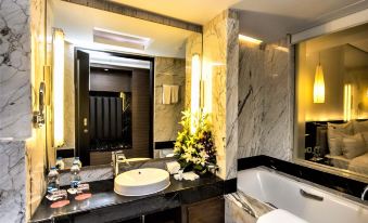 a luxurious bathroom with marble walls , a bathtub , and a sink , as well as a large mirror above the sink at Le Meridien Coimbatore