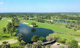a bird 's eye view of a golf course with green grass , water , and palm trees at Suwan Golf & Country Club