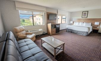 a hotel room with a couch , coffee table , and tv , as well as a bed , desk , and window at Red Sands Hotel
