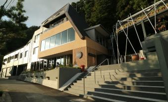 a modern building with a staircase leading up to the entrance , surrounded by trees and other buildings at Mizno Hotel