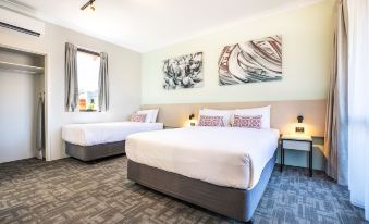 a hotel room with two beds , one on the left side and the other on the right side of the room at Nightcap at Wanneroo Tavern